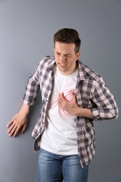 Photo of Young man having heart attack on color background