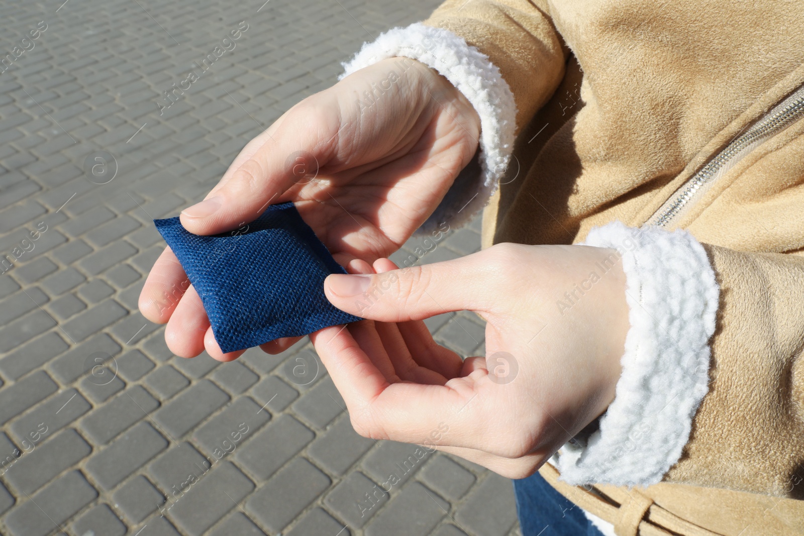 Photo of Woman holding hand warmer outdoors, closeup view