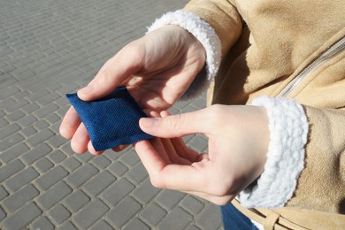 Woman holding hand warmer outdoors, closeup view