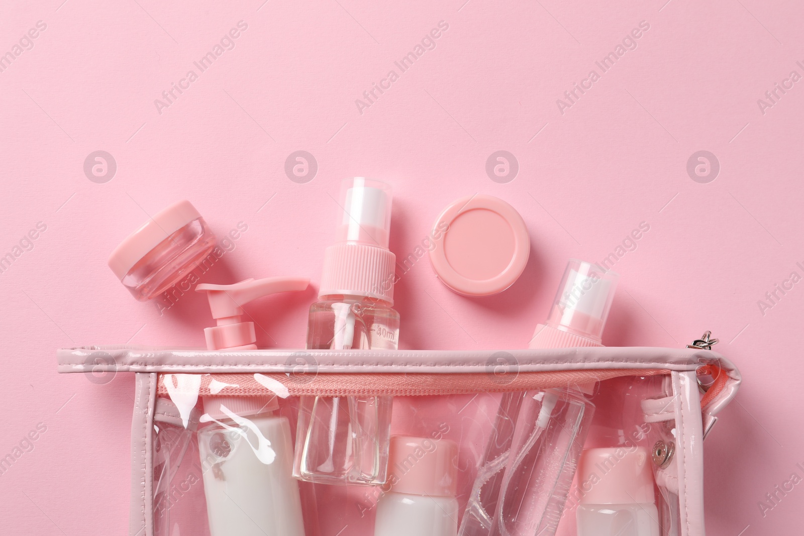 Photo of Plastic bag with cosmetic travel kit on pink background, flat lay. Bath accessories