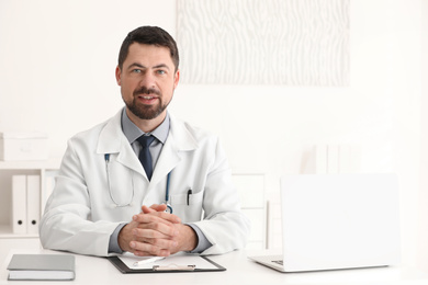 Portrait of male doctor in white coat at workplace