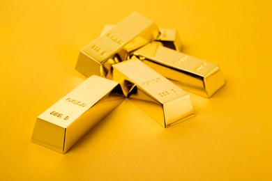 Photo of Precious shiny gold bars on color background