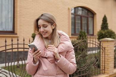 Photo of Beautiful young woman using mobile phone outdoors