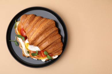 Photo of Tasty croissant with fried egg, tomato and microgreens on beige background, top view. Space for text