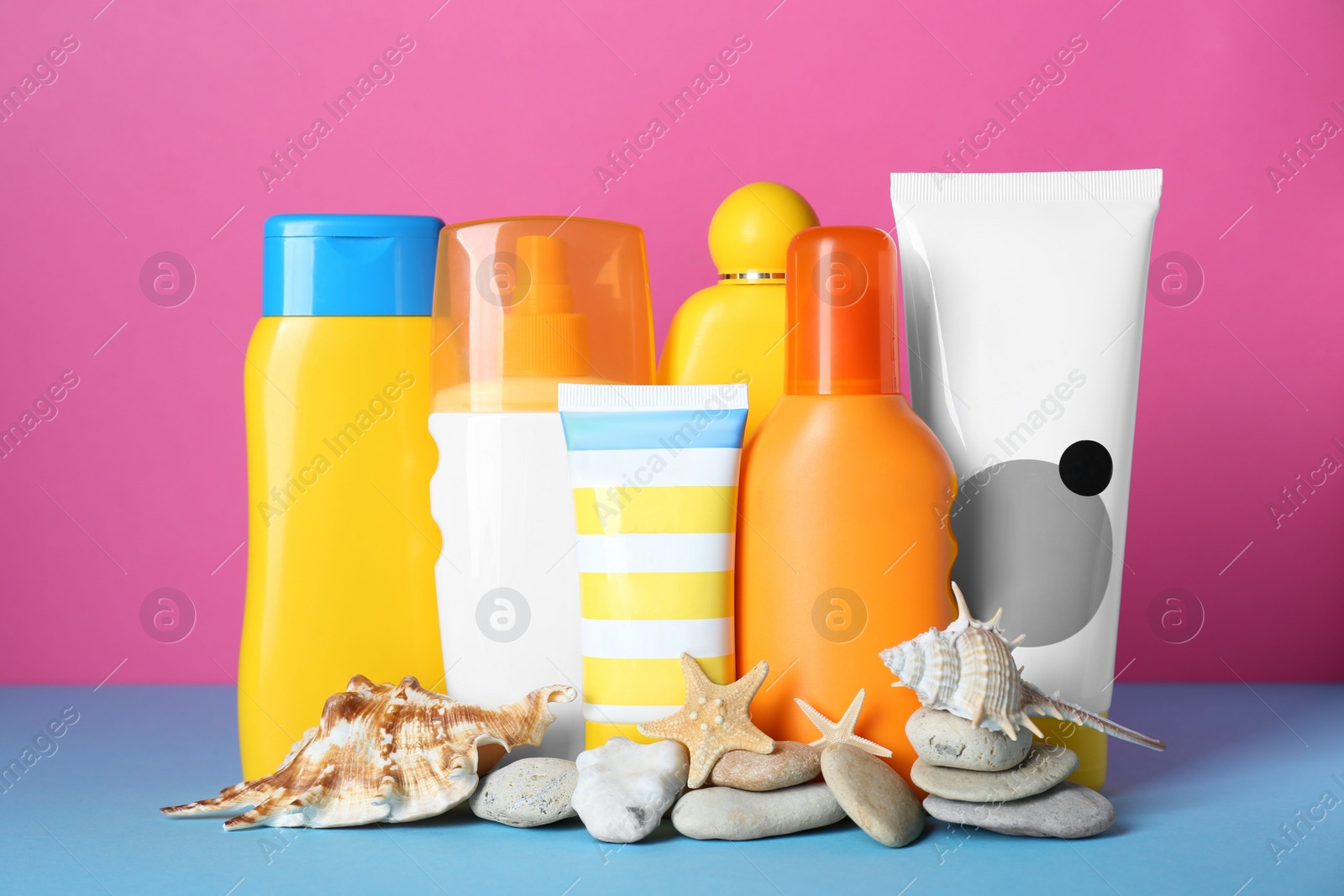 Photo of Different suntan products, seashells and starfishes on color background