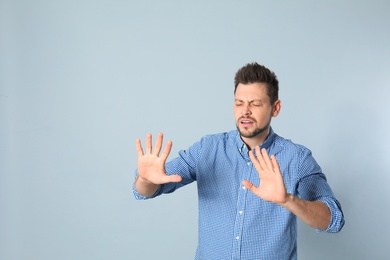 Handsome man being blinded on grey background