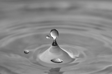 Photo of Splash of clear water with drops on grey background, closeup