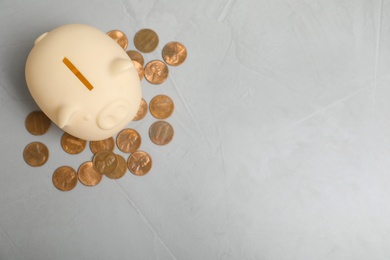 Photo of Piggy bank with coins and space for text on table, top view