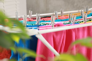 Clean laundry hanging on drying rack indoors