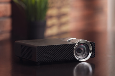 Photo of Modern video projector on wooden table indoors