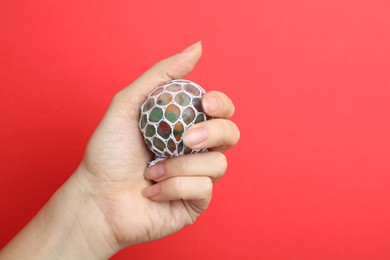 Photo of Woman holding colorful slime on red background, closeup. Antistress toy