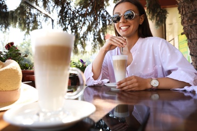 Beautiful young woman with coffee at table in outdoor cafe
