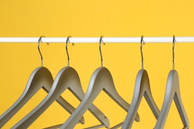 Photo of Metal rack with clothes hangers on color background