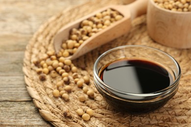 Soy sauce in bowl and beans on wooden table, closeup. Space for text