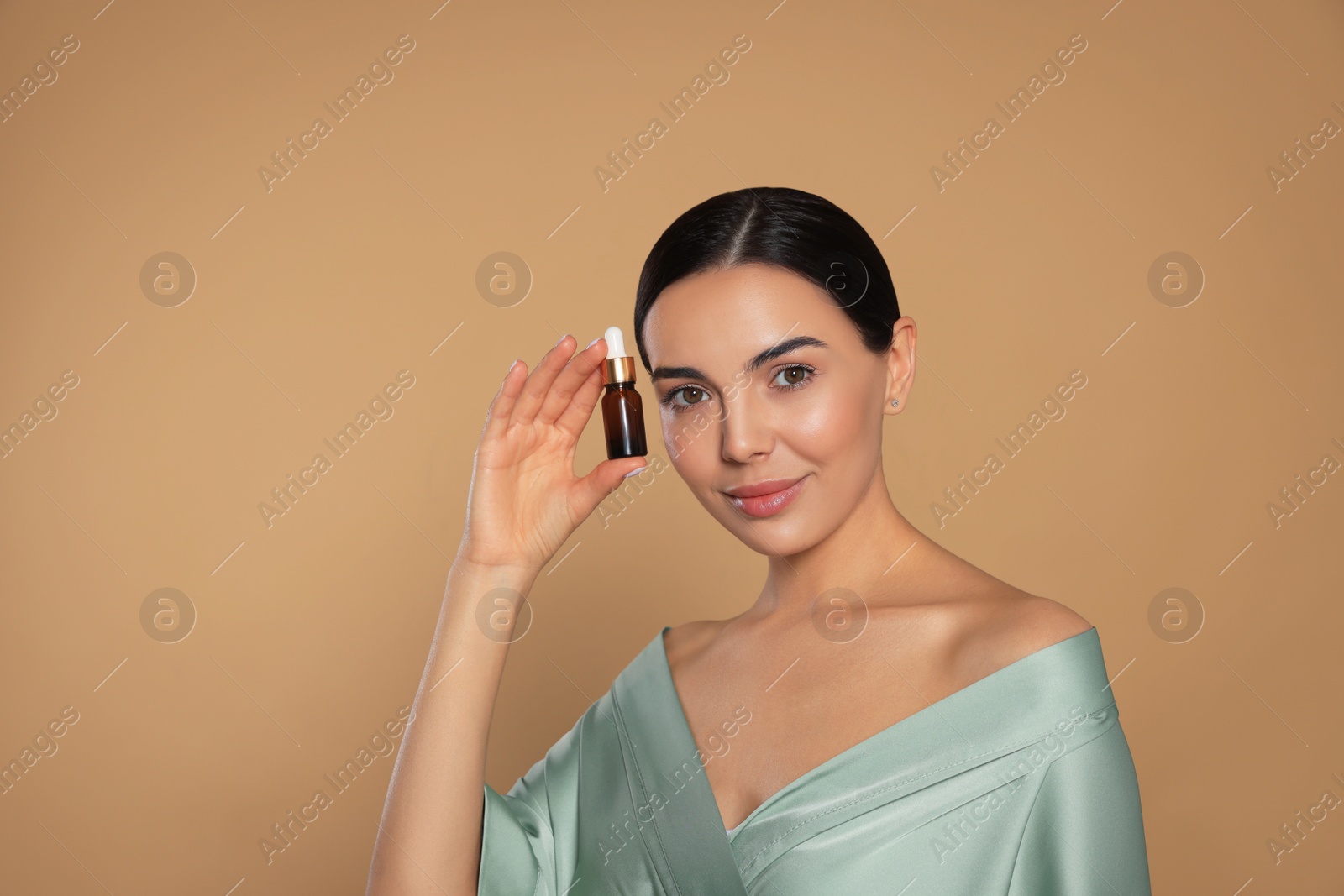 Photo of Young woman with bottle of essential oil on beige background. Space for text