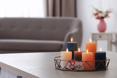 Photo of Tray with burning candles and flowers on table in living room. Space for text