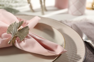 Pink fabric napkin with beautiful decorative ring for table setting on plate, closeup