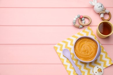 Photo of Pacifier, toys and plastic dishware with healthy baby food on pink wooden table, flat lay. Space for text