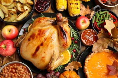 Photo of Traditional Thanksgiving day feast with delicious cooked turkey and other seasonal dishes served on wooden table, top view