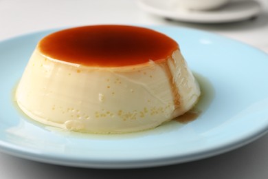 Delicious pudding with caramel on white table, closeup