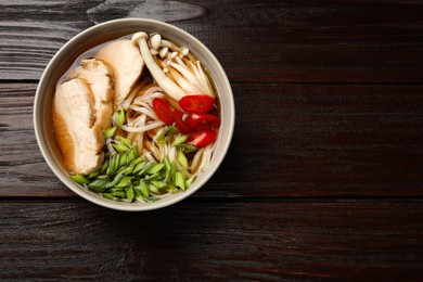 Photo of Delicious ramen with meat and mushrooms in bowl on wooden table, top view. Space for text