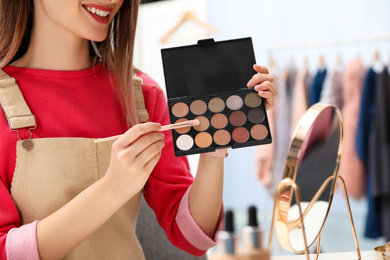 Photo of Beauty blogger with brush and eyeshadow palette at home, closeup