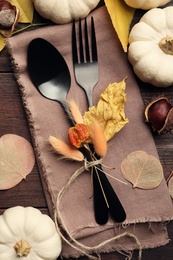 Photo of Seasonal table setting. Cutlery with pumpkins and autumn leaves on wooden background, flat lay