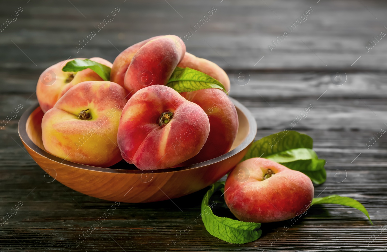 Photo of Fresh ripe donut peaches on black wooden table