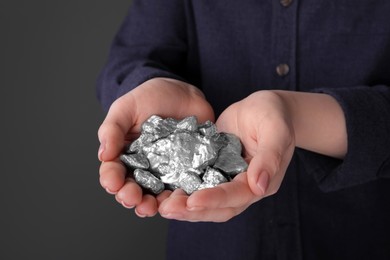 Woman with silver nuggets on black background, closeup