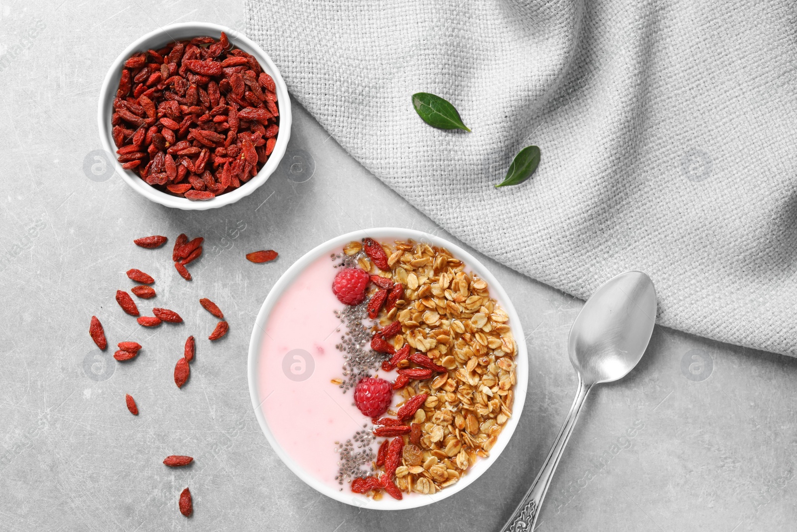 Photo of Smoothie bowl with goji berries on grey table, flat lay