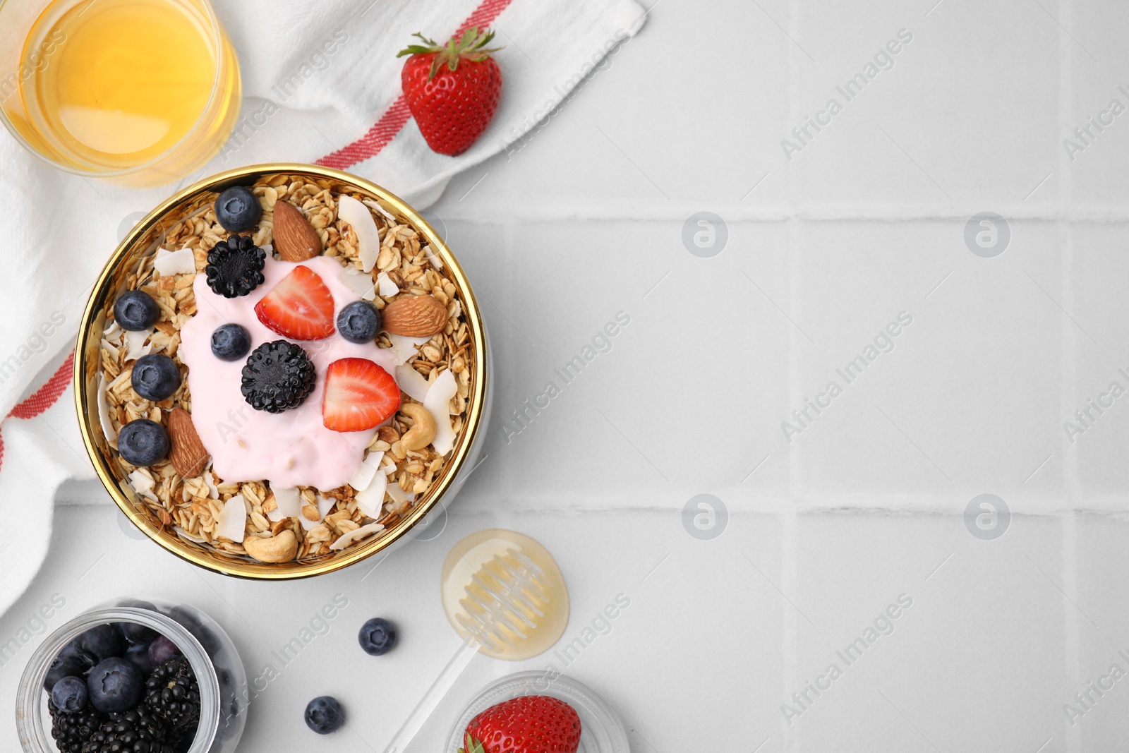 Photo of Tasty granola, yogurt and fresh berries served on white tiled table, flat lay with space for text. Healthy breakfast
