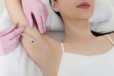 Photo of Cosmetologist injecting young woman's armpit, closeup. Treatment of hyperhidrosis