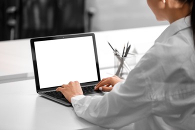 Woman using modern laptop at white desk in office, closeup