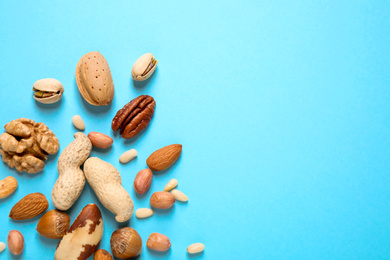 Photo of Different delicious nuts on light blue background, flat lay. Space for text