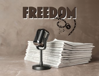 Image of Freedom of speech. Newspapers and microphone on light brown marble table. Illustration of broken chain