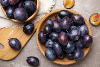 Delicious ripe plums on grey marble table, flat lay