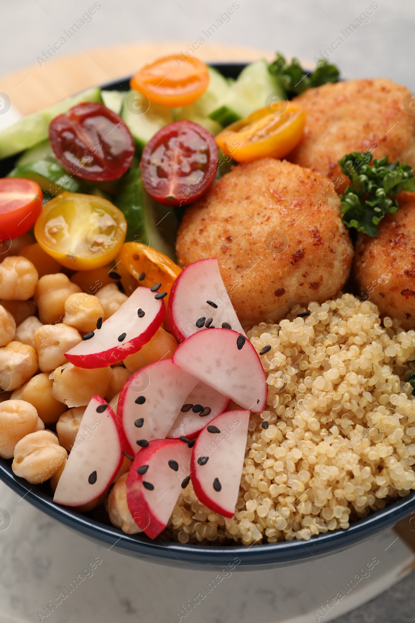 Photo of Delicious vegan bowl with chickpeas, cutlets and radish on table, closeup