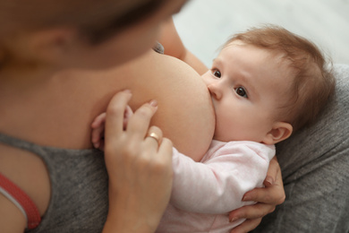 Young woman breastfeeding her baby at home, closeup