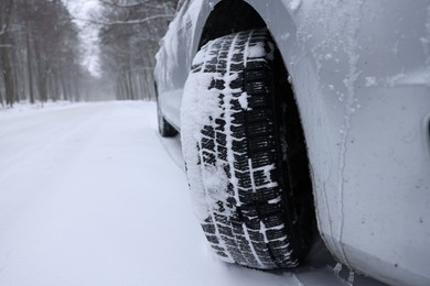Car with winter tires on snowy road outdoors, closeup. Space for text