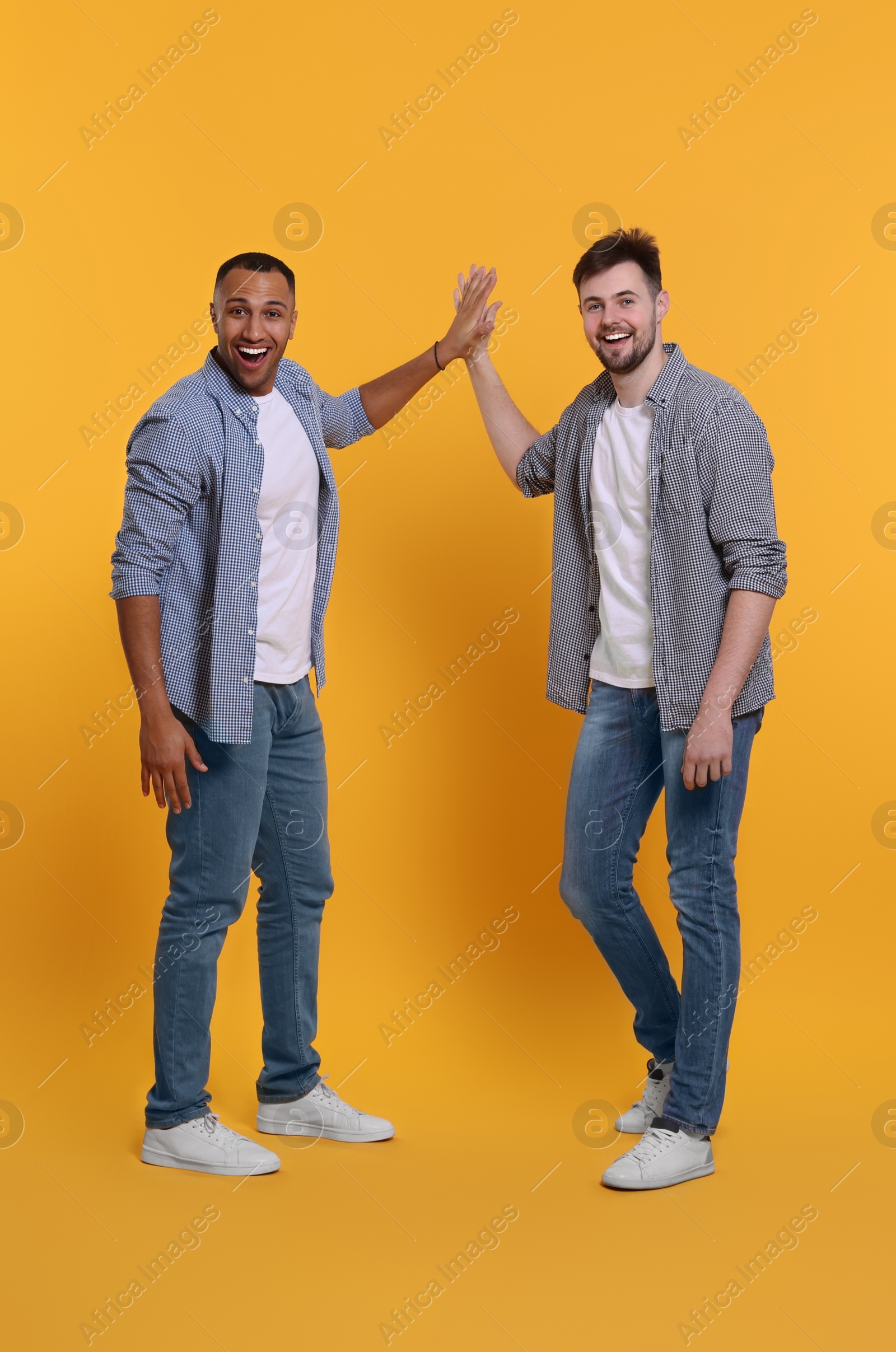 Photo of Men giving high five on yellow background