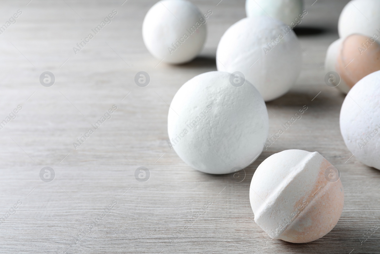 Photo of Many bath bombs on wooden table, space for text