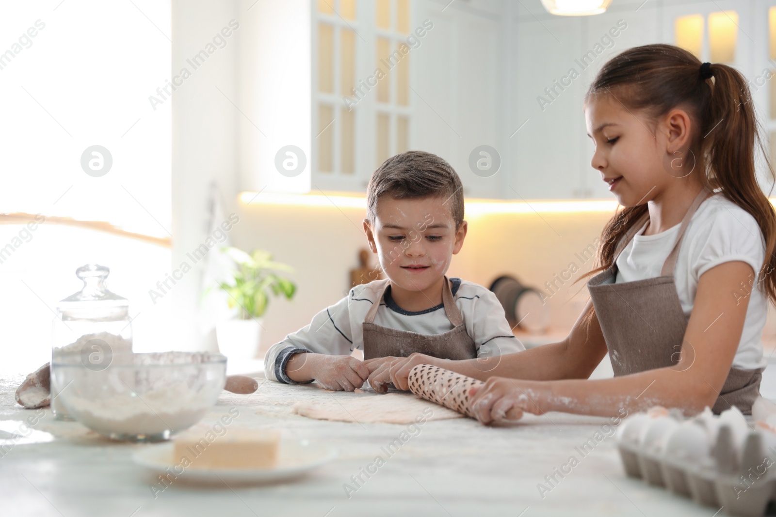 Photo of Cute little children cooking dough together in kitchen