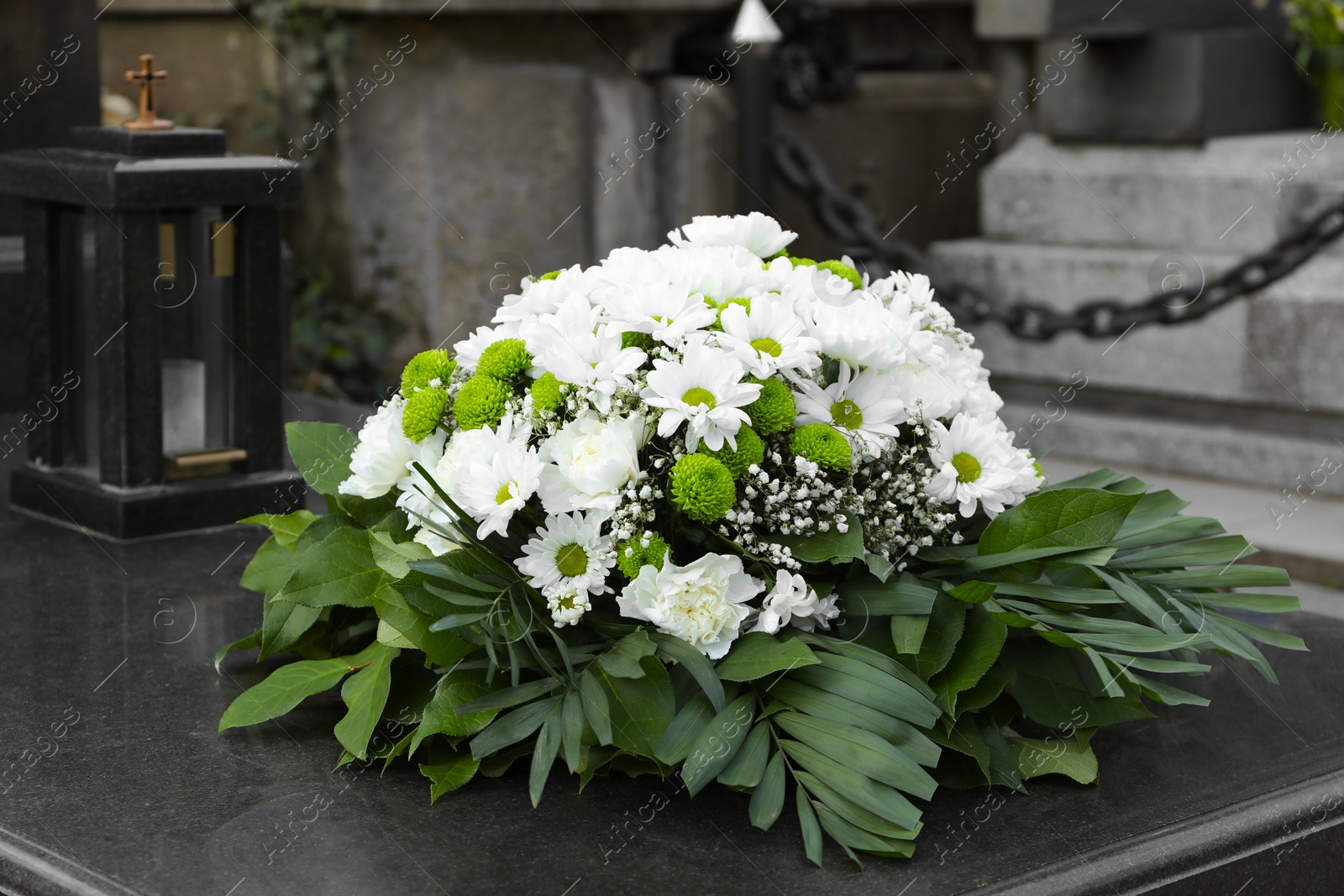 Photo of Funeral wreath of flowers on granite tombstone in cemetery