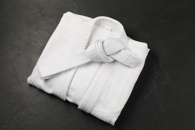 White karate belt and kimono on gray background, top view