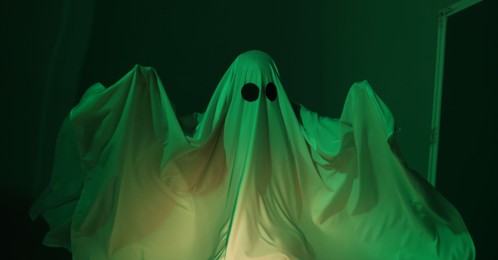 Creepy ghost. Woman covered with sheet in green light