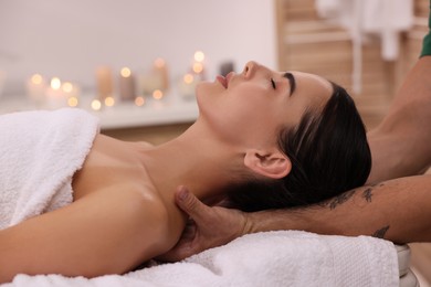 Woman receiving professional neck massage on couch in spa salon