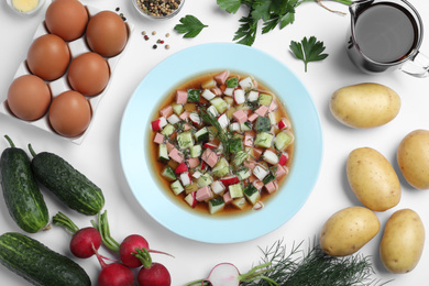 Photo of Cold okroshka with kvass and ingredients on white background, top view. Traditional Russian summer soup