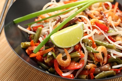 Photo of Shrimp stir fry with noodles and vegetables in wok on table, closeup