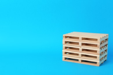 Photo of Stack of wooden pallets on light blue background, space for text