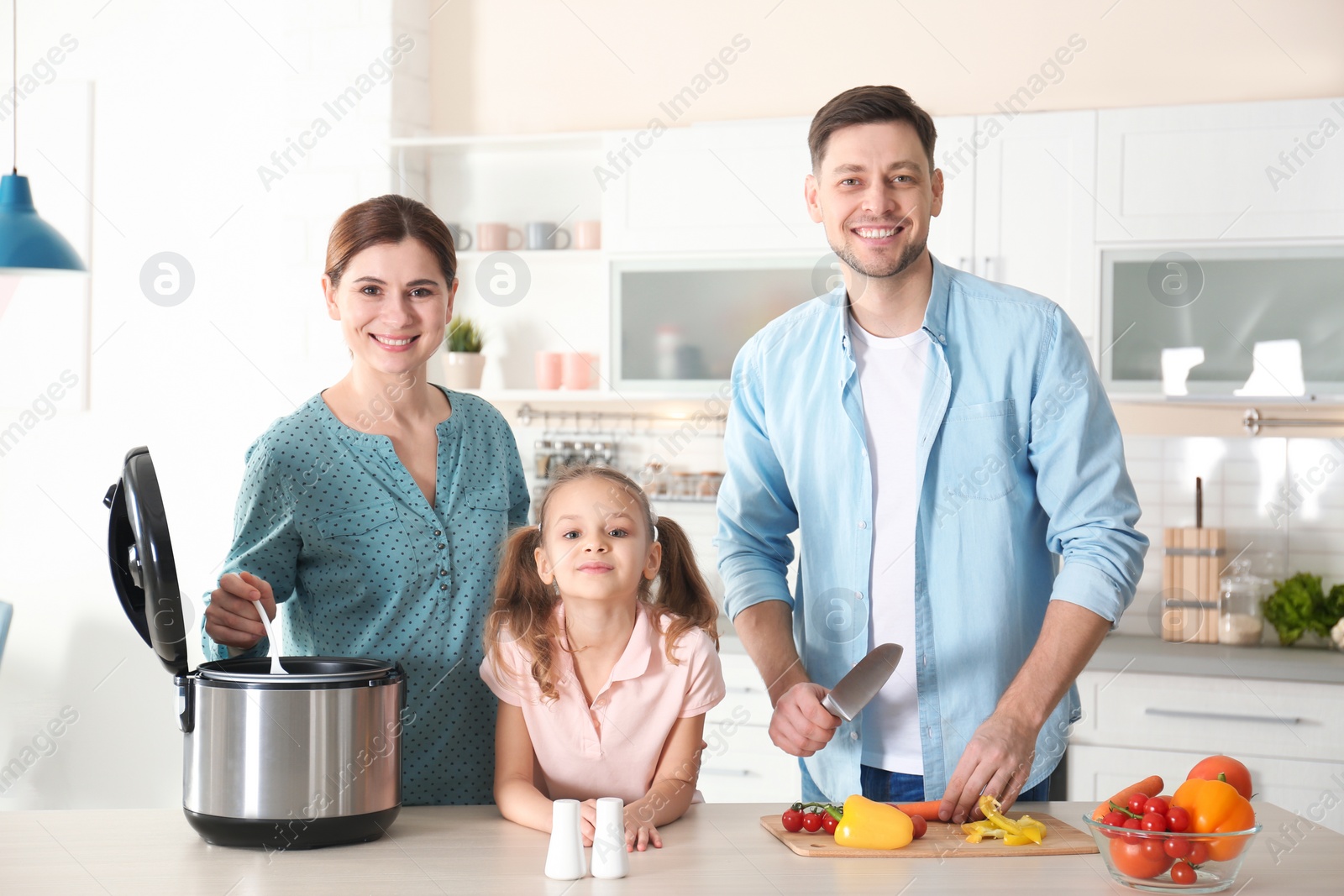 Photo of Happy family preparing food with modern multi cooker in kitchen